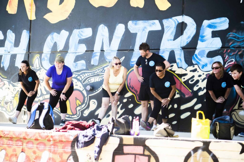 A group of people standing in front of a graffiti wall.